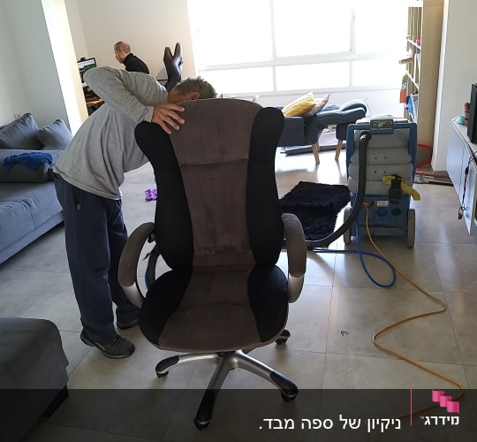 אדם מנקה כיסא עם מכונת ניקוי מקצועית